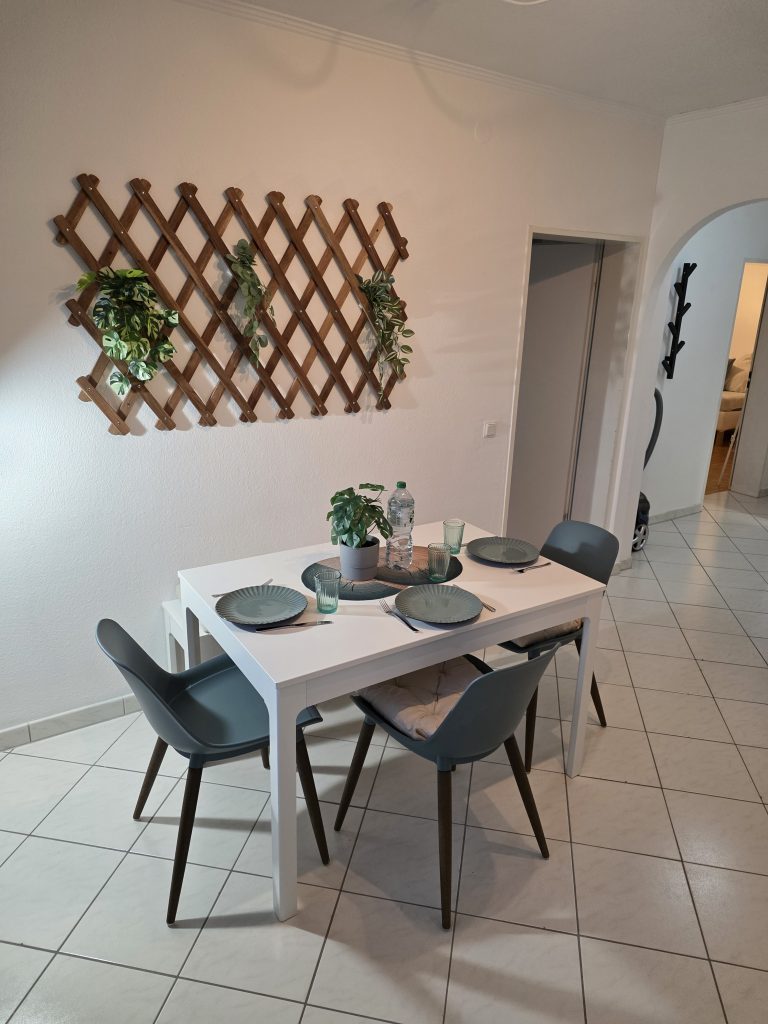 Esstisch mit Stühlen und Rankgitter an der Wand
