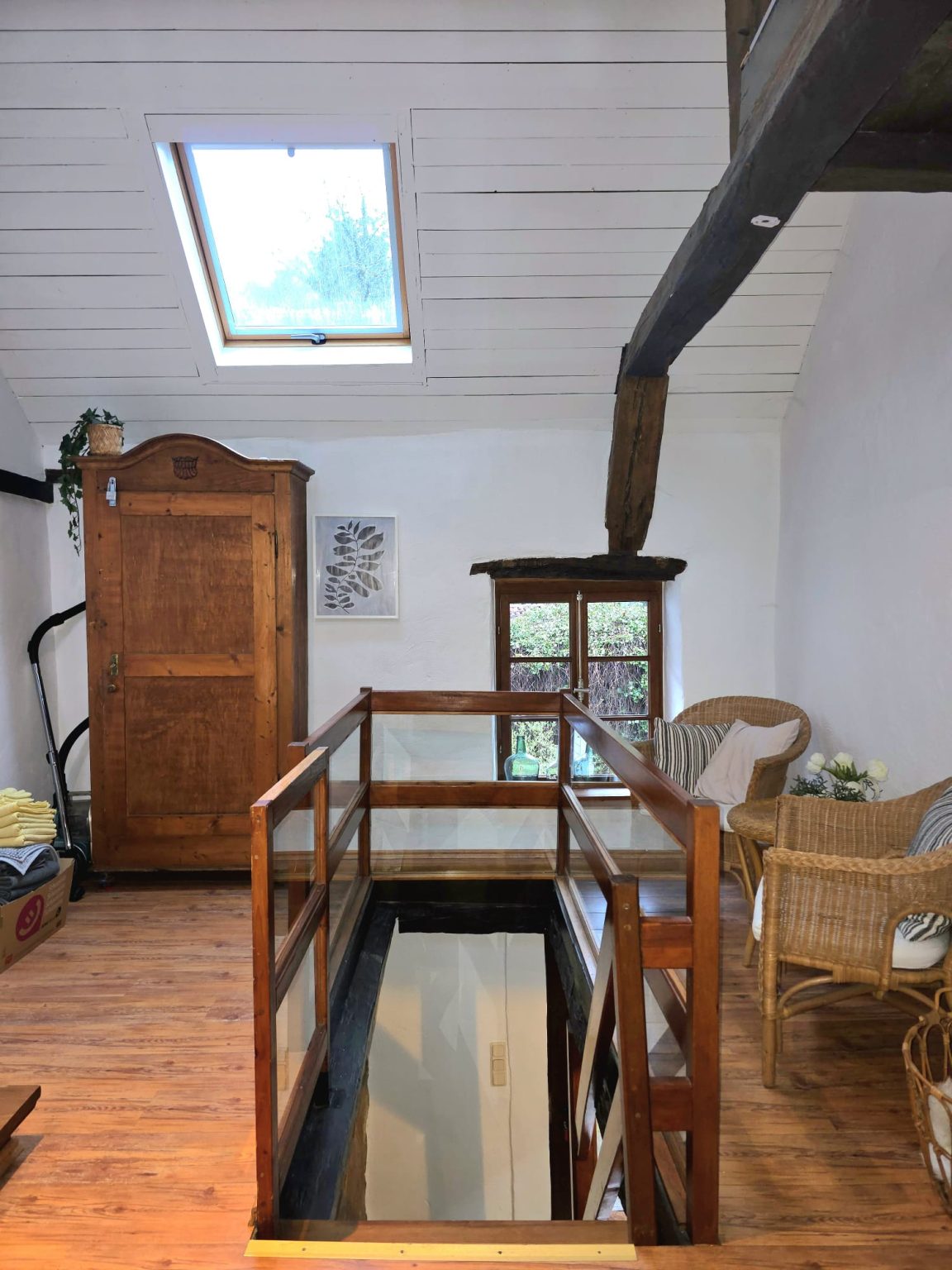 Empore im Obergeschoss mit Holzschrank, Dachfenster und Rattansesseln
