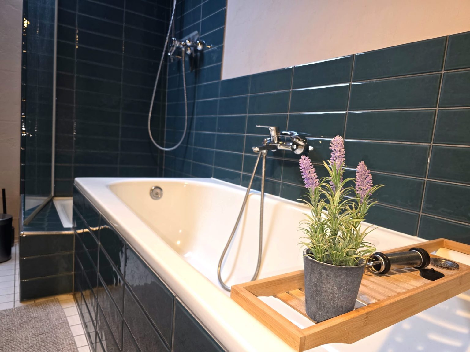 Badewanne mit Ablage und Lavendel vor blauen Fliesen