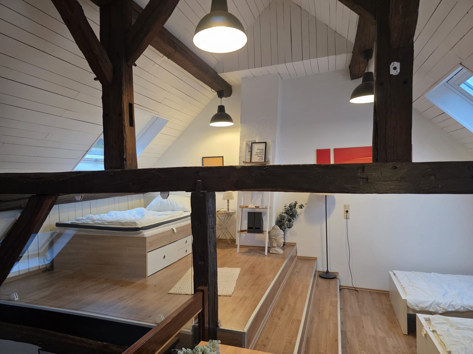 Offenes Schlafzimmer im Dachgeschoss mit Holzbalken und Betten