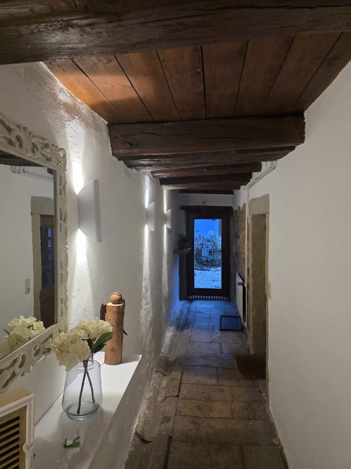 Flur mit Holzbalkendecke, Wandleuchten und Spiegel im Bauernhaus